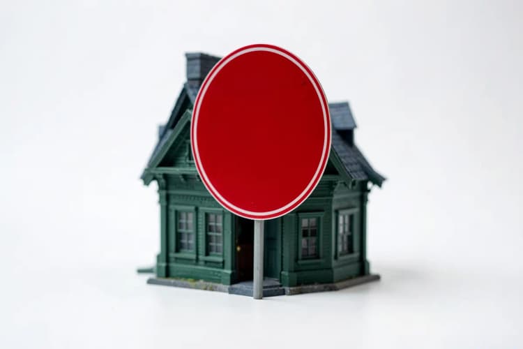 Uma casa com um sinal de proibido sobre ela.