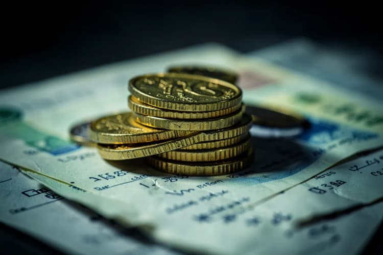 Uma pilha de moedas de ouro e notas de dinheiro em cima de um contrato.